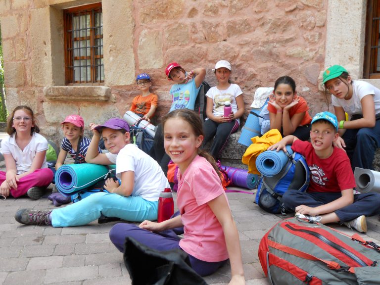 Niños de excursión con sus mochilas sentados en un pueblo